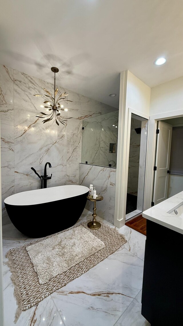 bathroom with vanity, an inviting chandelier, and a washtub