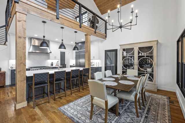 dining area with sink, hardwood / wood-style flooring, high vaulted ceiling, and a chandelier