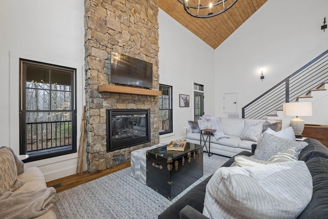 living room with hardwood / wood-style flooring, a stone fireplace, high vaulted ceiling, and wooden ceiling