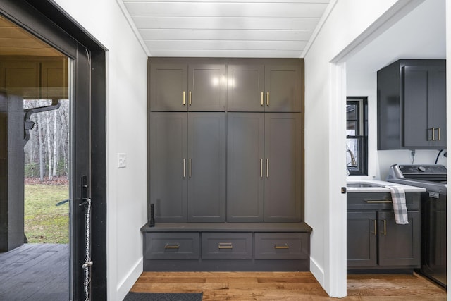 mudroom with washer / clothes dryer, sink, and light wood-type flooring