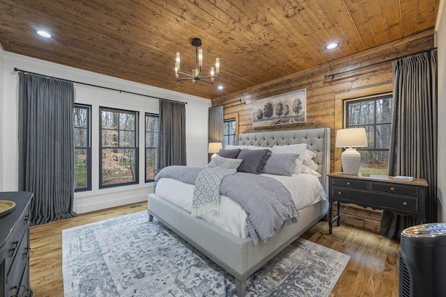 bedroom with an inviting chandelier, wood-type flooring, rustic walls, and wooden ceiling