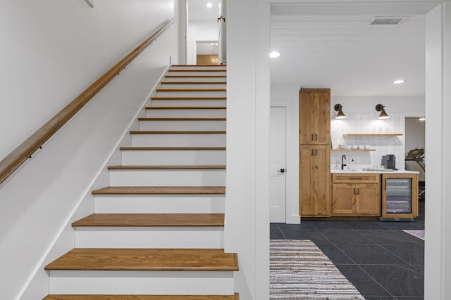 stairs with tile patterned floors, beverage cooler, and indoor wet bar