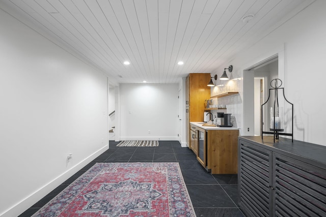 kitchen featuring dark tile patterned flooring, wooden ceiling, and sink