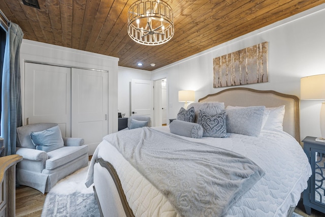 bedroom featuring an inviting chandelier, wood-type flooring, ornamental molding, wooden ceiling, and a closet