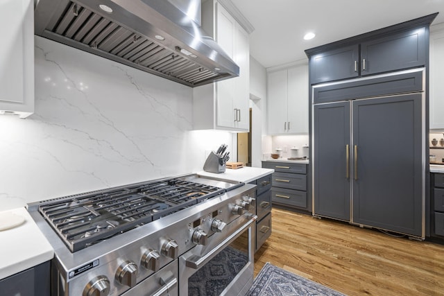 kitchen featuring white cabinetry, extractor fan, light hardwood / wood-style flooring, and premium appliances