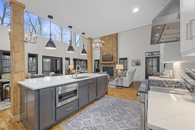 kitchen featuring sink, a chandelier, hanging light fixtures, stainless steel microwave, and gray cabinets