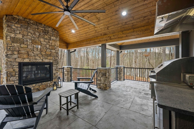 view of patio / terrace with ceiling fan, an outdoor stone fireplace, and an outdoor kitchen