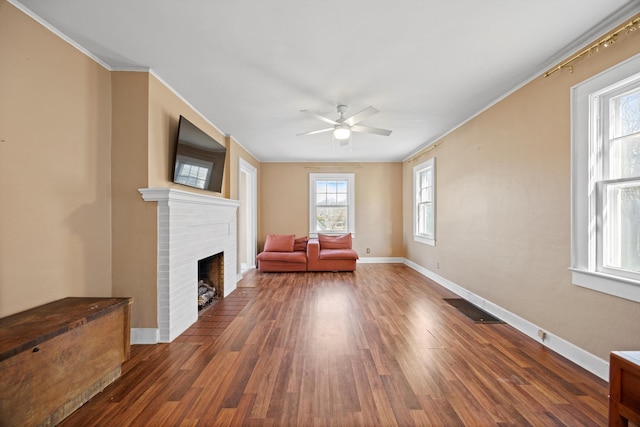 unfurnished room featuring ceiling fan, crown molding, a fireplace, and dark hardwood / wood-style floors