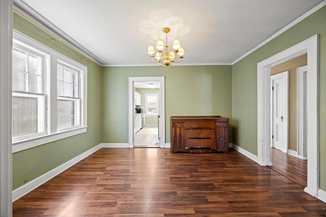 interior space with dark wood-type flooring, ornamental molding, a healthy amount of sunlight, and a notable chandelier