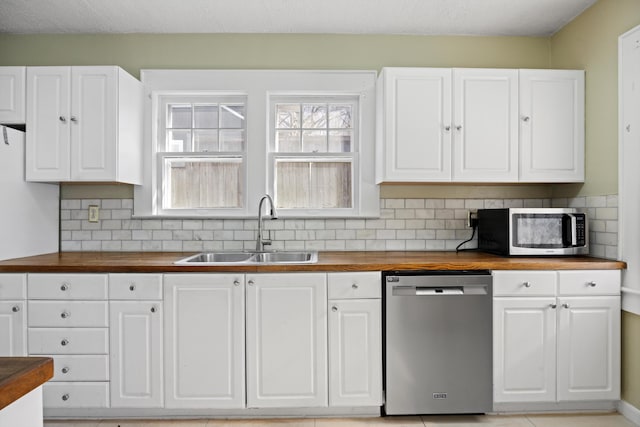 kitchen with backsplash, sink, stainless steel appliances, white cabinets, and butcher block counters