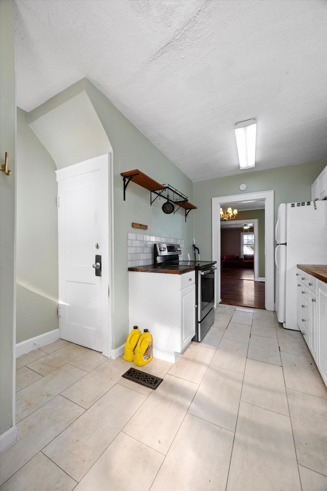 kitchen featuring tasteful backsplash, stainless steel electric range, light tile patterned flooring, white cabinetry, and white refrigerator