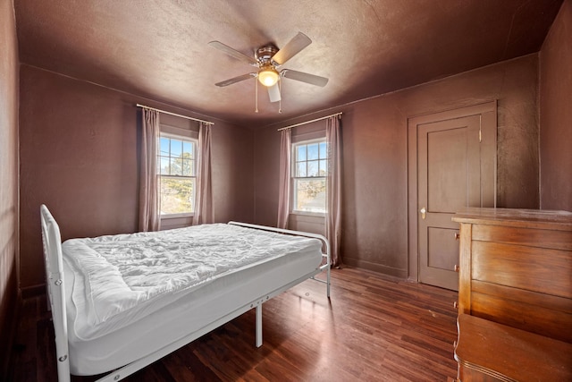 bedroom with ceiling fan, dark hardwood / wood-style flooring, and a textured ceiling