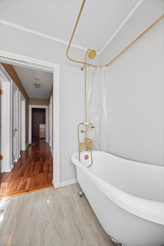 bathroom with hardwood / wood-style flooring, shower / bath combo with shower curtain, and crown molding