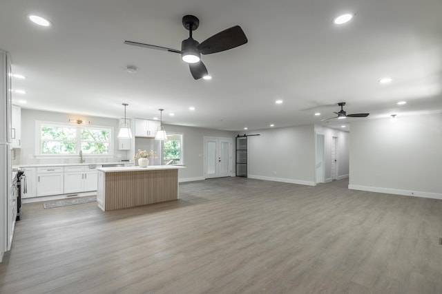 kitchen featuring ceiling fan, white cabinets, a center island, and light wood-type flooring