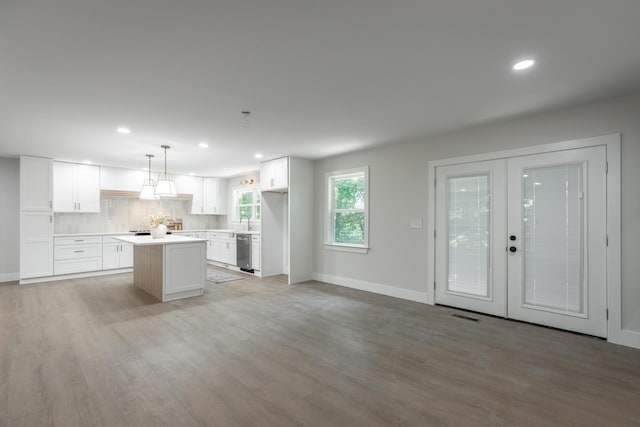 kitchen with dishwasher, pendant lighting, a kitchen island, decorative backsplash, and white cabinets