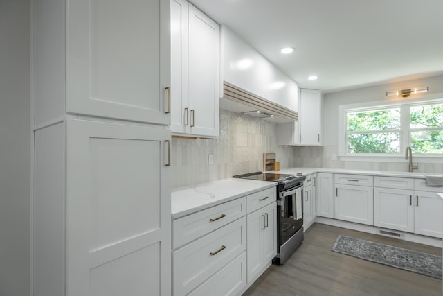 kitchen with backsplash, sink, hardwood / wood-style flooring, stainless steel range with electric stovetop, and white cabinets