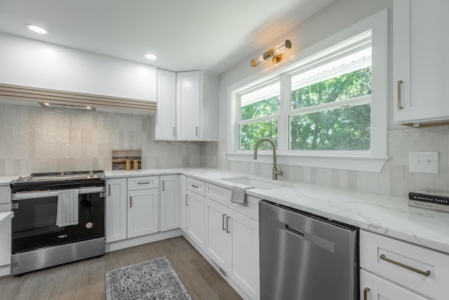 kitchen featuring appliances with stainless steel finishes, backsplash, white cabinets, light stone counters, and sink