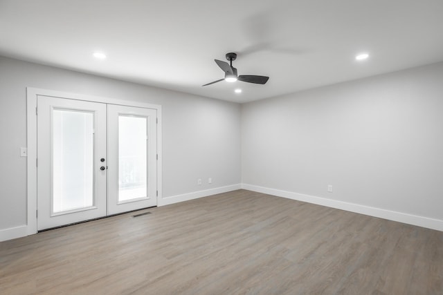 empty room with ceiling fan, light hardwood / wood-style floors, and french doors