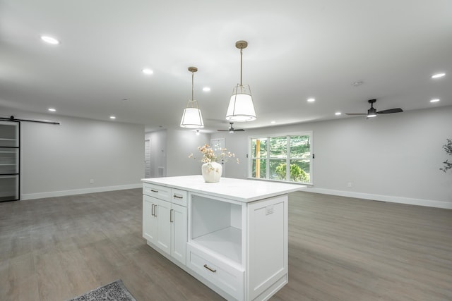 kitchen featuring pendant lighting, a kitchen island, white cabinetry, ceiling fan, and a barn door