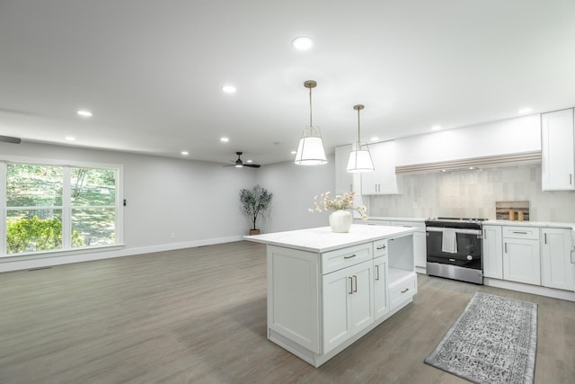 kitchen with pendant lighting, white cabinets, a center island, stainless steel range oven, and backsplash