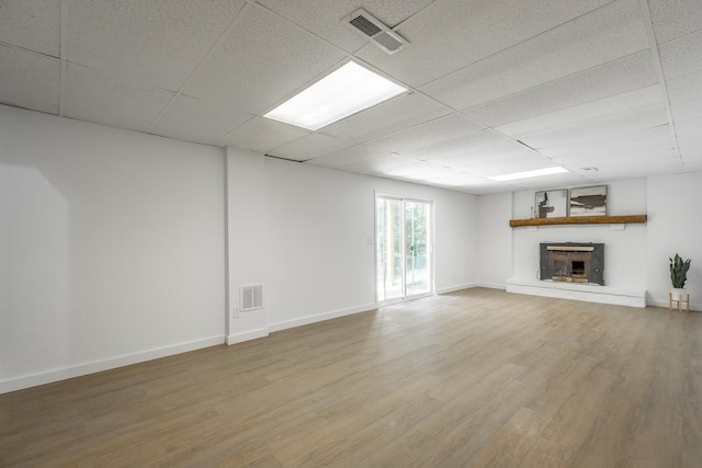 unfurnished living room featuring wood-type flooring and a drop ceiling