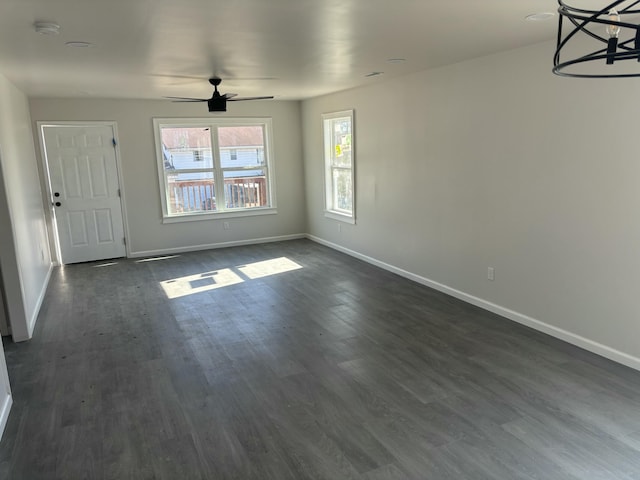 unfurnished living room featuring ceiling fan with notable chandelier and dark hardwood / wood-style flooring