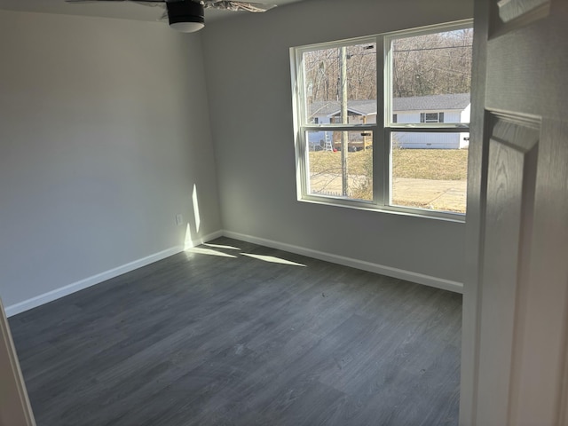 empty room with ceiling fan, a wealth of natural light, and dark hardwood / wood-style flooring