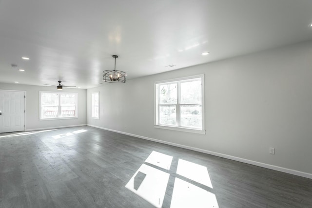 unfurnished room with ceiling fan with notable chandelier and dark hardwood / wood-style flooring