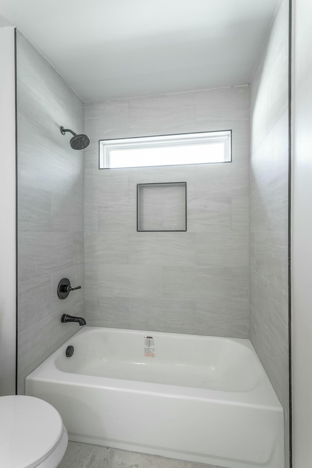 bathroom featuring toilet and tiled shower / bath combo