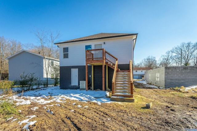 snow covered house with cooling unit and a wooden deck