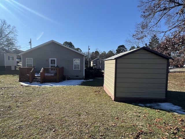 back of property featuring a wooden deck, a lawn, and a shed