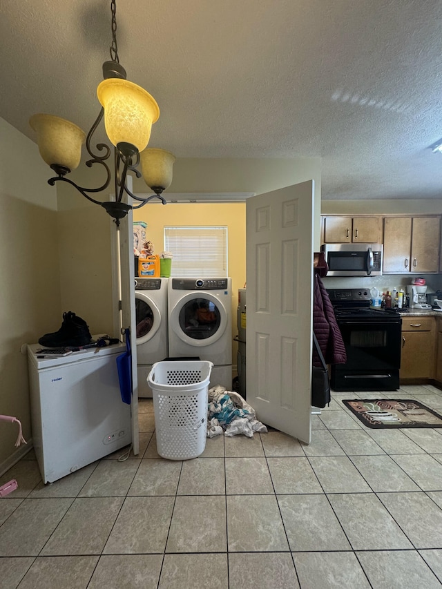 washroom featuring washer and dryer, a textured ceiling, an inviting chandelier, and light tile patterned flooring