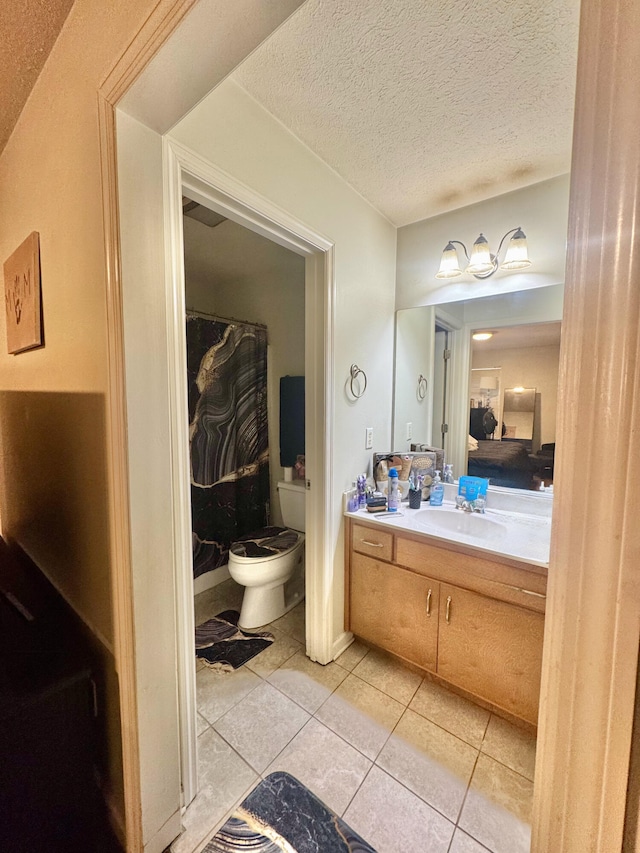 bathroom featuring toilet, a textured ceiling, tile patterned floors, and vanity