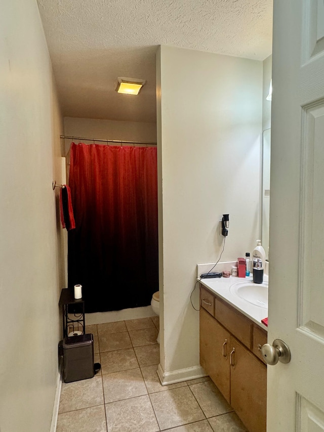 bathroom with toilet, vanity, tile patterned flooring, walk in shower, and a textured ceiling