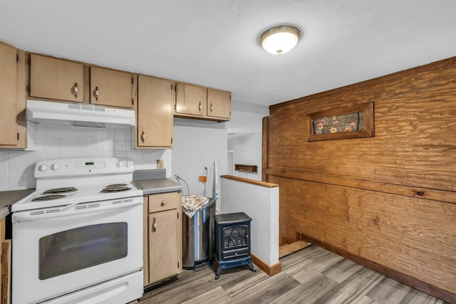 kitchen featuring backsplash, white range with electric stovetop, a wood stove, and light wood-type flooring