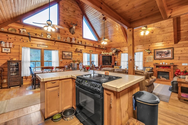 kitchen featuring tile counters, high vaulted ceiling, black electric range oven, light hardwood / wood-style flooring, and beamed ceiling