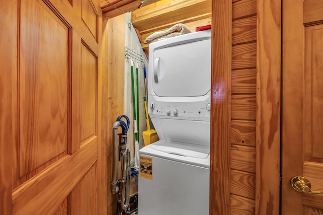 laundry area featuring stacked washer / dryer and wood walls