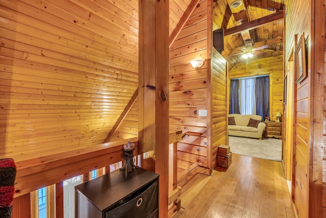 hall featuring log walls, wood ceiling, wood walls, lofted ceiling with beams, and light hardwood / wood-style flooring