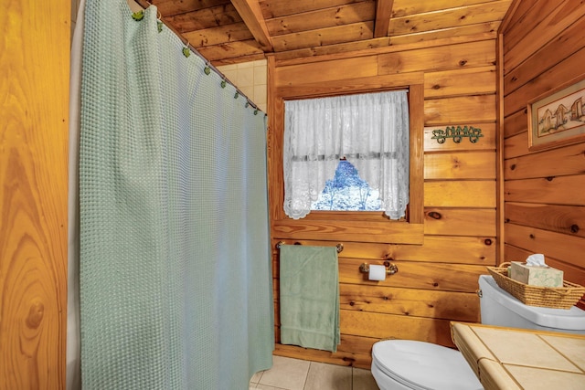 bathroom with toilet, wood walls, wooden ceiling, tile patterned floors, and beamed ceiling