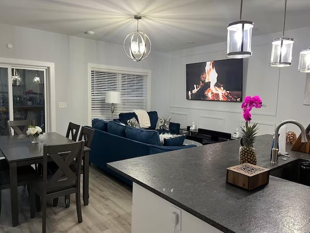 kitchen featuring sink, an inviting chandelier, white cabinetry, light hardwood / wood-style flooring, and hanging light fixtures