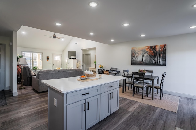 kitchen featuring dark wood-type flooring, ceiling fan, vaulted ceiling, and a center island