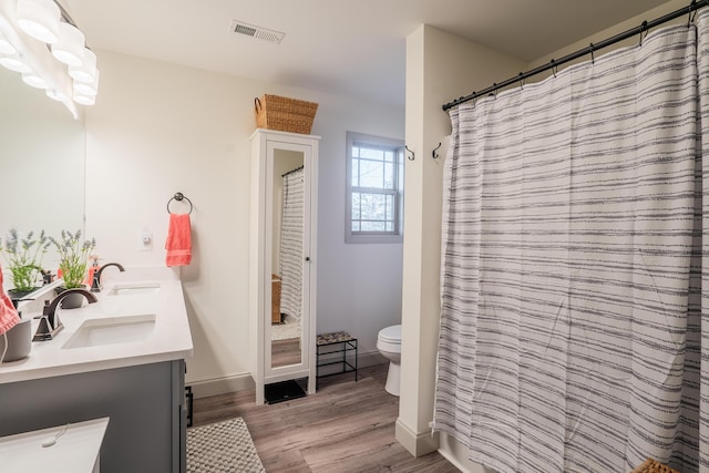 bathroom with hardwood / wood-style floors, toilet, vanity, and a shower with curtain