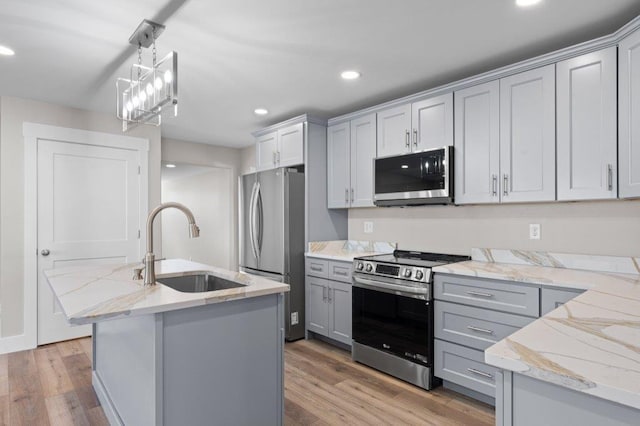 kitchen featuring gray cabinets, sink, light hardwood / wood-style flooring, hanging light fixtures, and stainless steel appliances