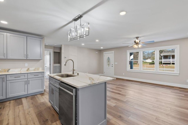 kitchen with gray cabinetry, an island with sink, dishwasher, and sink