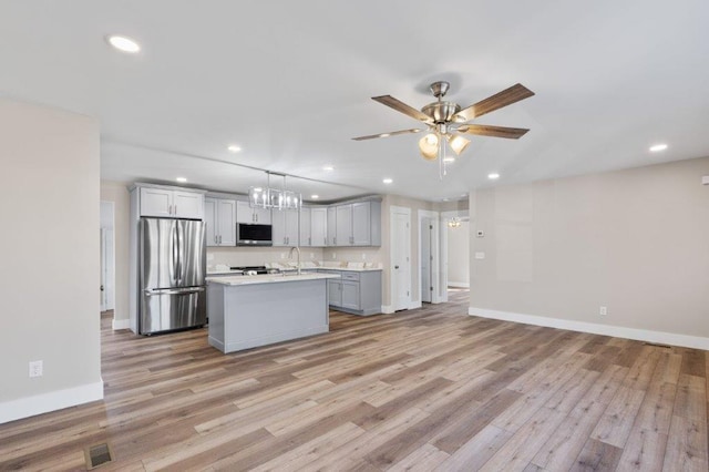 kitchen featuring gray cabinets, pendant lighting, light hardwood / wood-style flooring, a kitchen island with sink, and appliances with stainless steel finishes