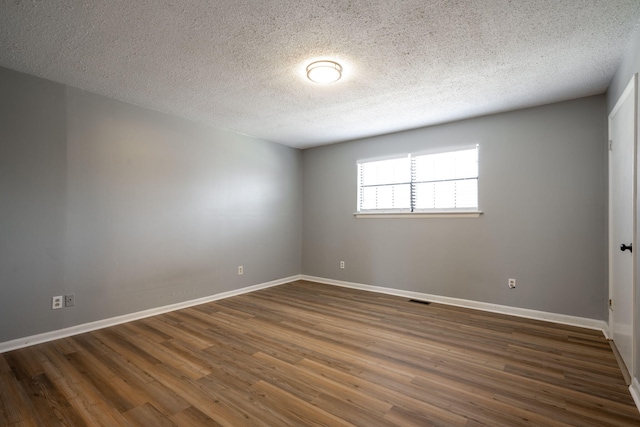 unfurnished room with a textured ceiling and dark hardwood / wood-style floors