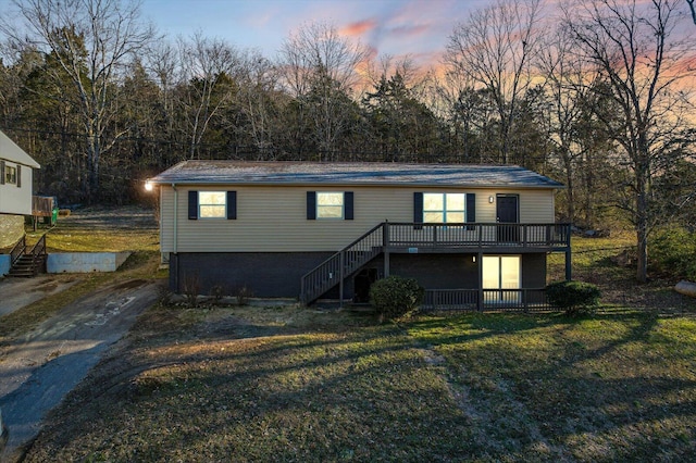 back house at dusk with a wooden deck and a yard