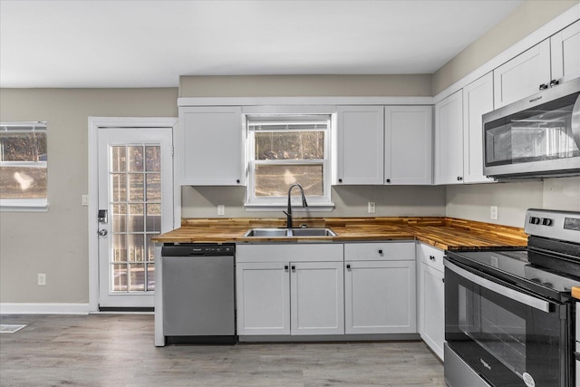 kitchen featuring sink, white cabinets, appliances with stainless steel finishes, and butcher block counters