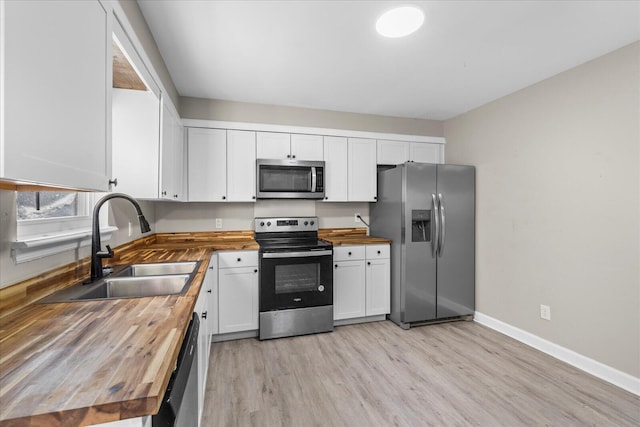 kitchen featuring wooden counters, sink, light wood-type flooring, stainless steel appliances, and white cabinets