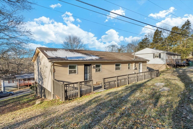 rear view of house with a lawn and a wooden deck